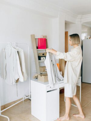 Woman sorting garments in a modern apartment, showcasing a clean, minimalist lifestyle.